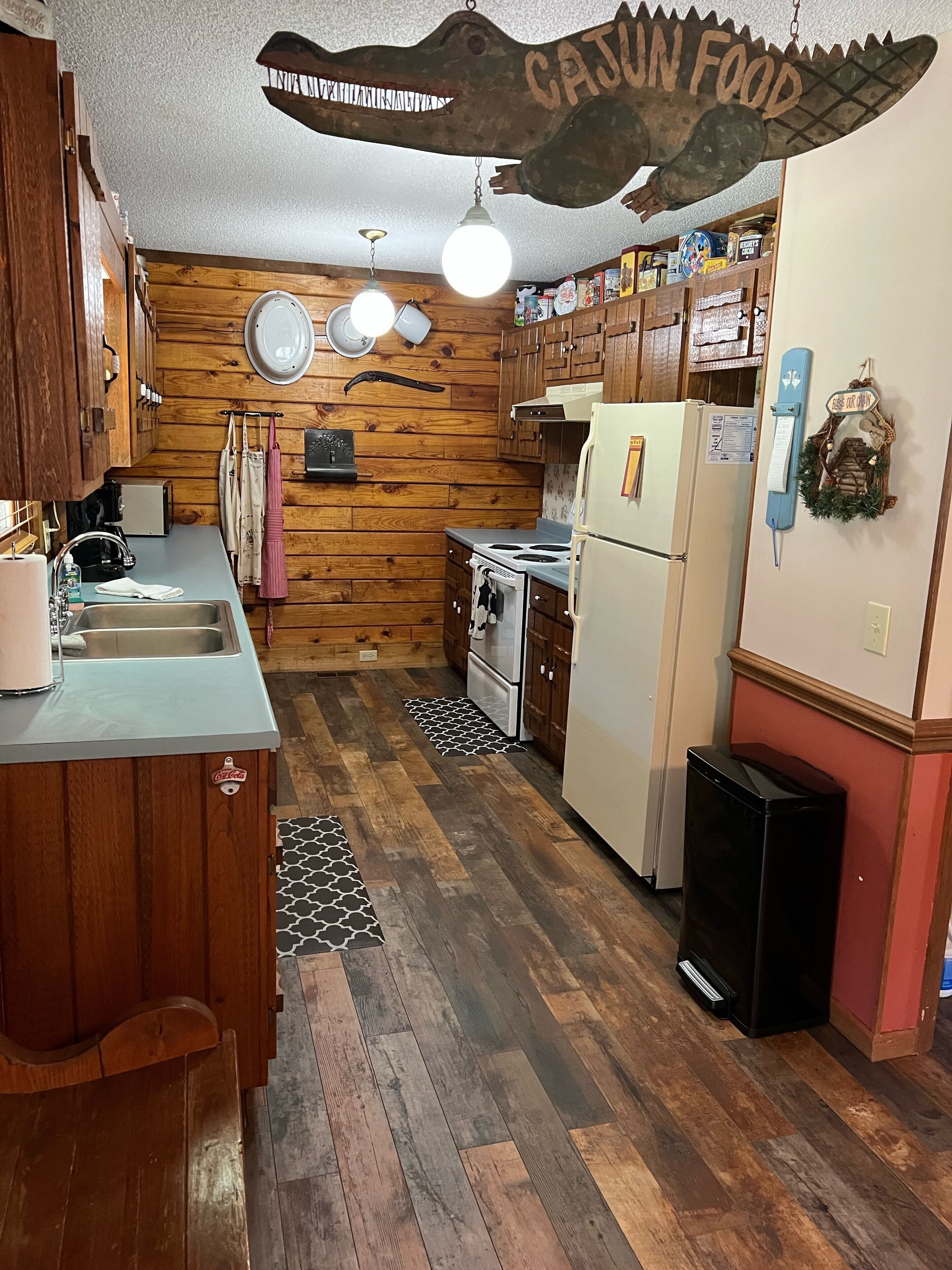A kitchen with wooden walls, a refrigerator, stove, and a sink.