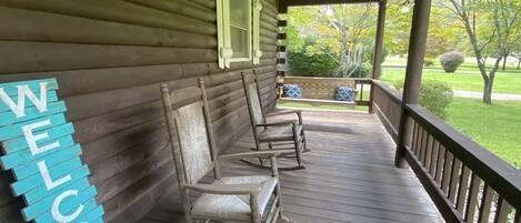 A wooden porch with rocking chairs and a 'WELCOME' sign.