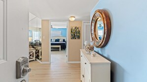 A hallway with a white door, a wooden dresser, and a mirror on the wall. - Xanadu II 605-3BR/3BA Oceanfront condo in Cherry Grove (North Myrtle Beach)