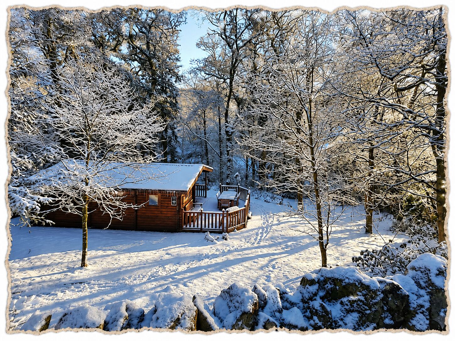 Una cabaña de madera con un balcón, rodeada de árboles cubiertos de nieve y un cielo despejado.