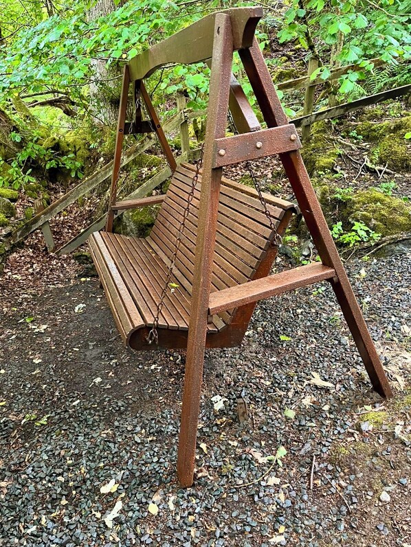 A rustic wooden swing set in a forested area. - Blelham Tarn (Rustic yet modern cabin in tranquil woodland with own EV charger) (Ambleside)