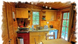 A compact kitchen with wooden cabinets, a red stove, and a sink. - Blelham Tarn (Rustic yet modern cabin in tranquil woodland with own EV charger) (Ambleside)