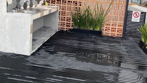 Un espace extérieur moderne comprenant un banc en béton, un évier en métal et un mur décoratif orné de carreaux hexagonaux.