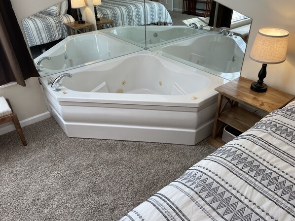 Relax in a spacious bathroom with a large bathtub and comfortable bed nearby.