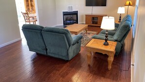 A living room with a fireplace, a television, and two green armchairs. - Matthew Estates Ranch (Dandridge)