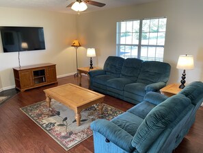 A living room with a blue sofa, wooden coffee table, and a TV mounted on the wall.