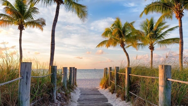 A wooden boardwalk leading to a beach with palm trees and a clear sky. - Sunny Beachside Retreat: Cozy 2 bed Townhouse! (Indialantic)