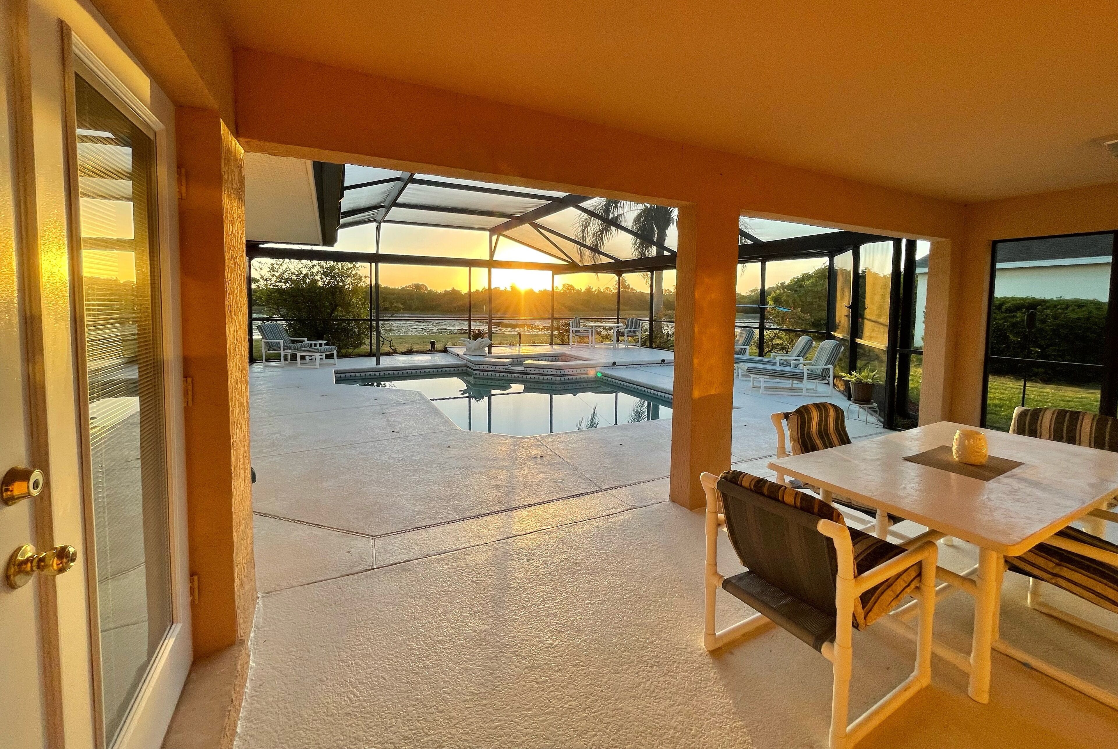 Une terrasse couverte avec une piscine, des sièges d’extérieur et une vue sur le coucher de soleil.