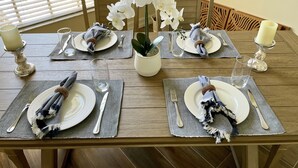 A dining table set with plates, cutlery, and candles, surrounded by chairs.