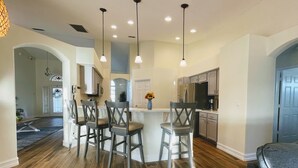 A modern kitchen with bar stools, a central island, and pendant lighting.