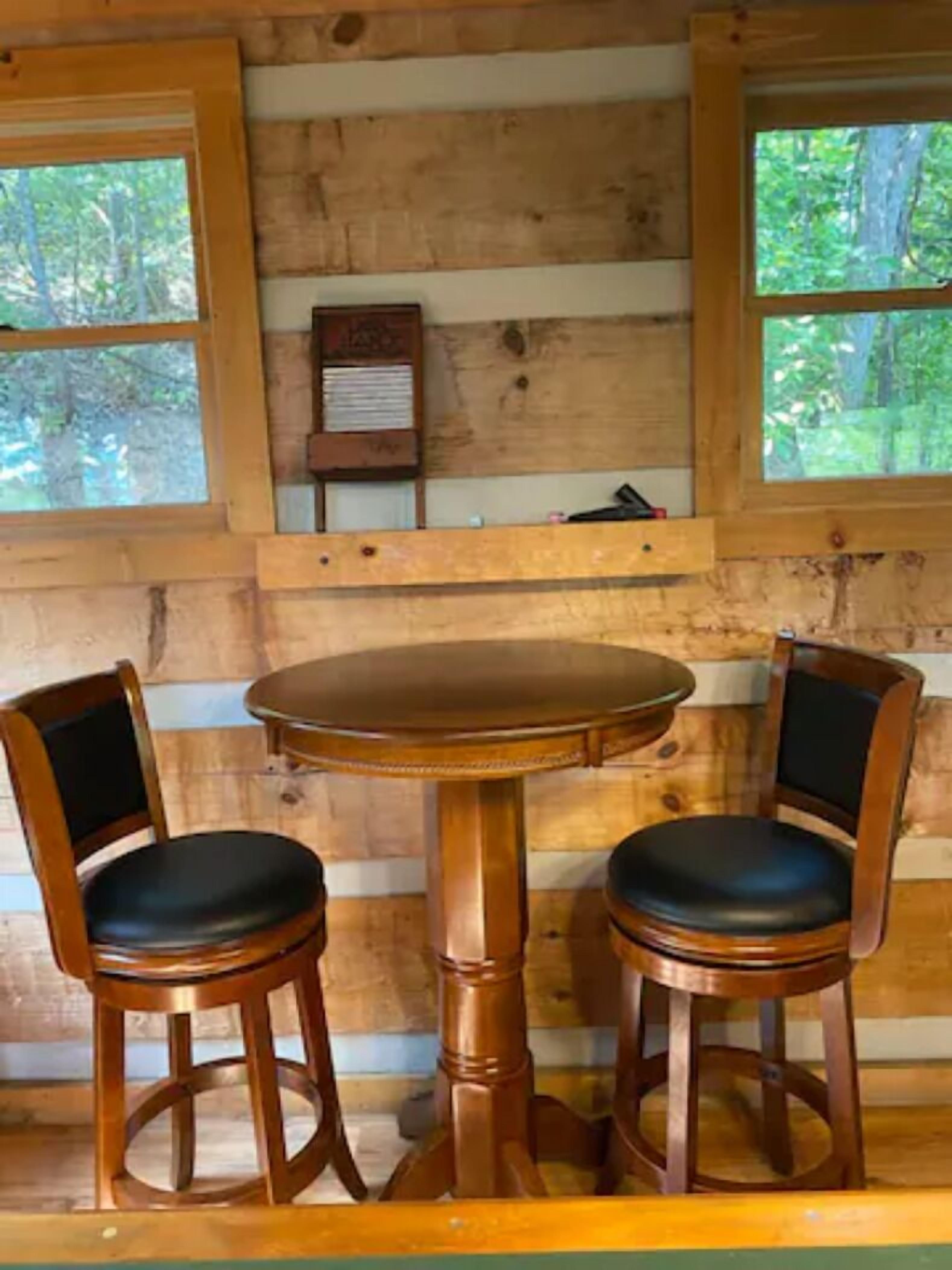 A wooden cabin interior with a round wooden table and two matching chairs.