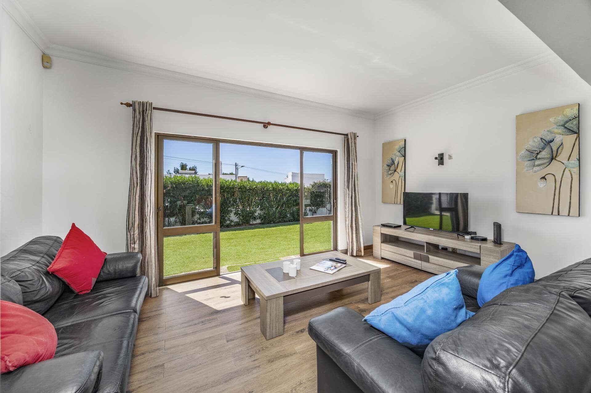 A modern living room with a large sliding glass door, a flat-screen TV, and a coffee table.