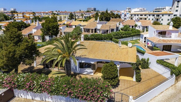 Zona residencial com edifícios brancos, uma palmeira e uma piscina.