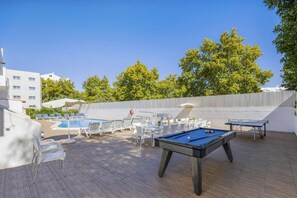 Un espace extérieur avec une piscine, des chaises longues, une table de billard et une table de ping-pong.