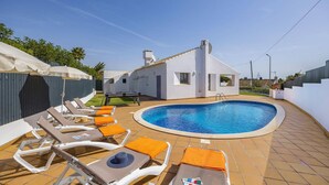 A swimming pool area with lounge chairs and a small building. - Villa Amendoeira by Villa Plus (Albufeira)