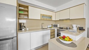 A modern kitchen with a stainless steel refrigerator, a microwave, a coffee maker, and a fruit bowl on the counter. - Villa Amendoeira by Villa Plus (Albufeira)