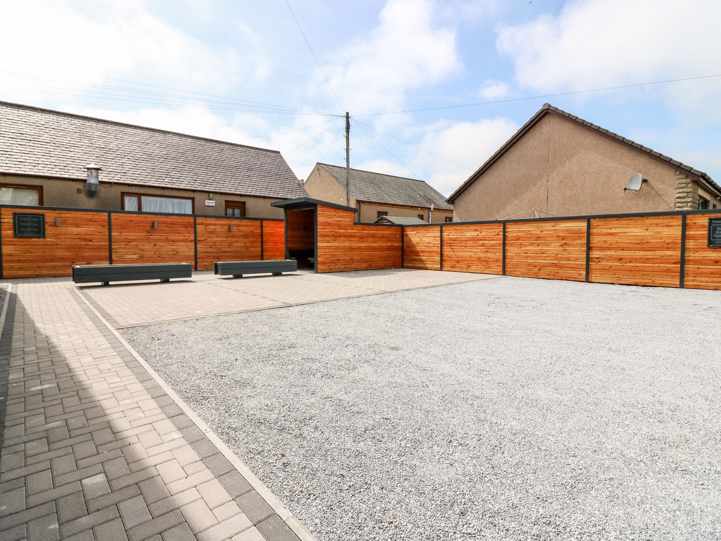 A building with a gravel courtyard, wooden benches, and a brick pathway.