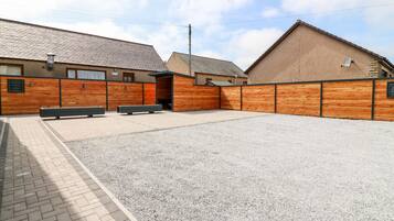 A building with a gravel courtyard, wooden benches, and a brick pathway.