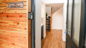 Een houten wand met een bord waarop 'The Marriage Room' staat, en een deur naar een trap.