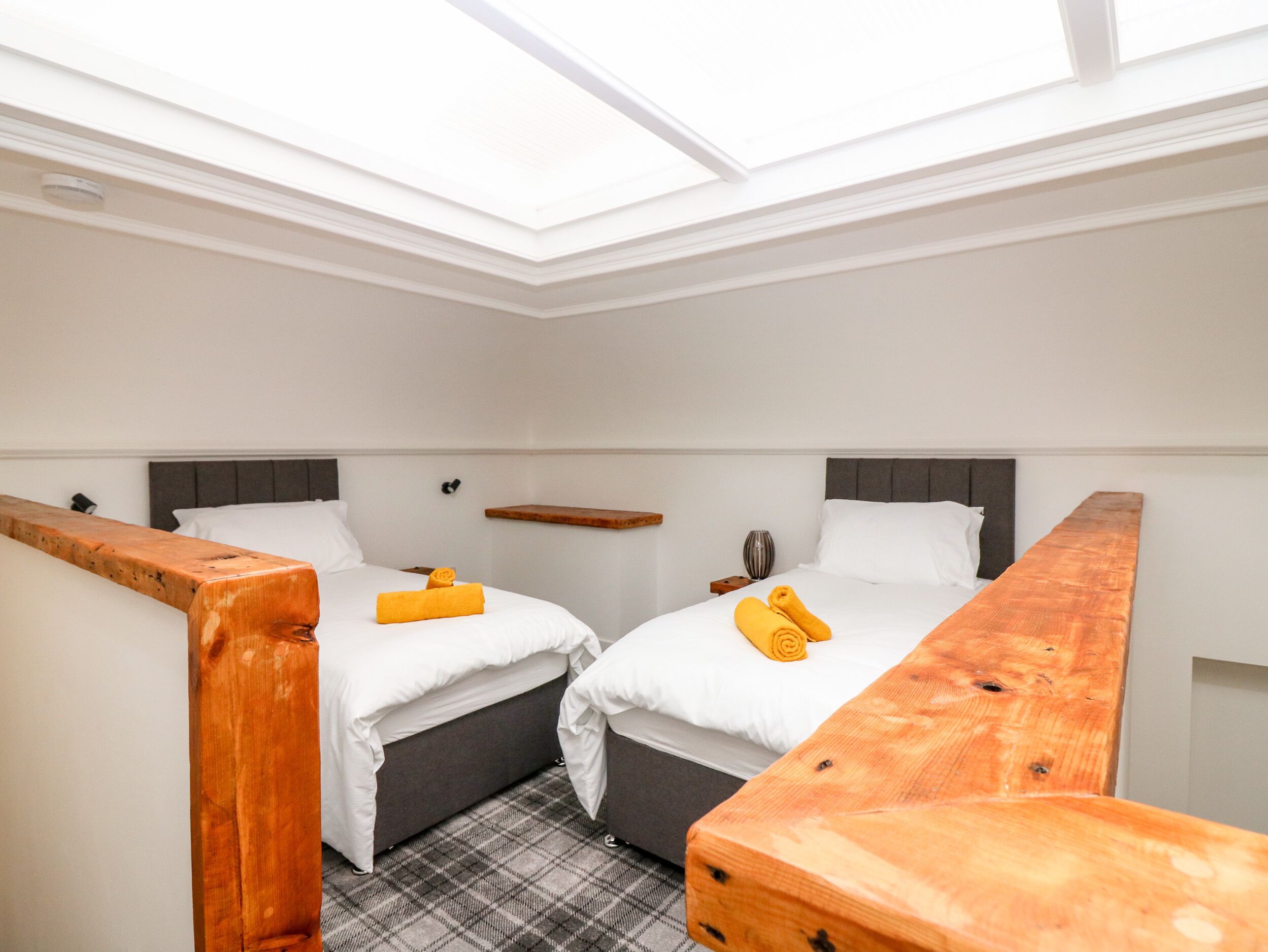 A small, modern room with two beds, a skylight, and a wooden bench.