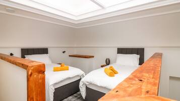 A small, modern room with two beds, a skylight, and a wooden bench.