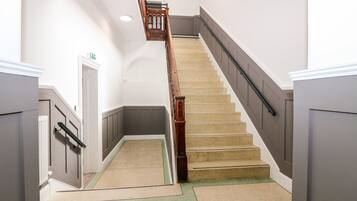 A modern staircase with a wooden handrail and beige carpeted steps.