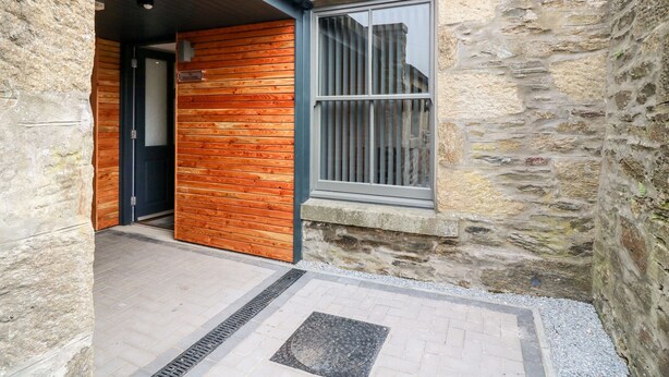 A stone building with a wooden door and a window with metal bars. - The Keepers Cottage at The Institute Executive Apartments (Keith)