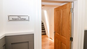 A hallway with a wooden door labeled "The Keepers Cottage." - The Keepers Cottage at The Institute Executive Apartments (Keith)