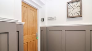 Ein Flur mit einer Holztür, einer an der Wand befestigten Uhr und einem Schild mit der Aufschrift 'The Clock Tower'.