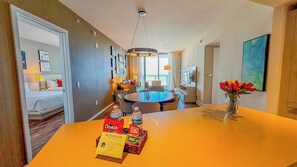 Une chambre d’hôtel comprenant un lit, un coin repas avec une table et des chaises, un lustre et un vase rempli de fleurs.