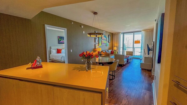 A modern interior with a central island, a dining area, and a view of the city.