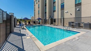 A rectangular swimming pool with clear blue water, surrounded by a tiled deck and a metal fence. - Comfort Inn & Suites Balch Springs - SE Dallas (Mesquite)