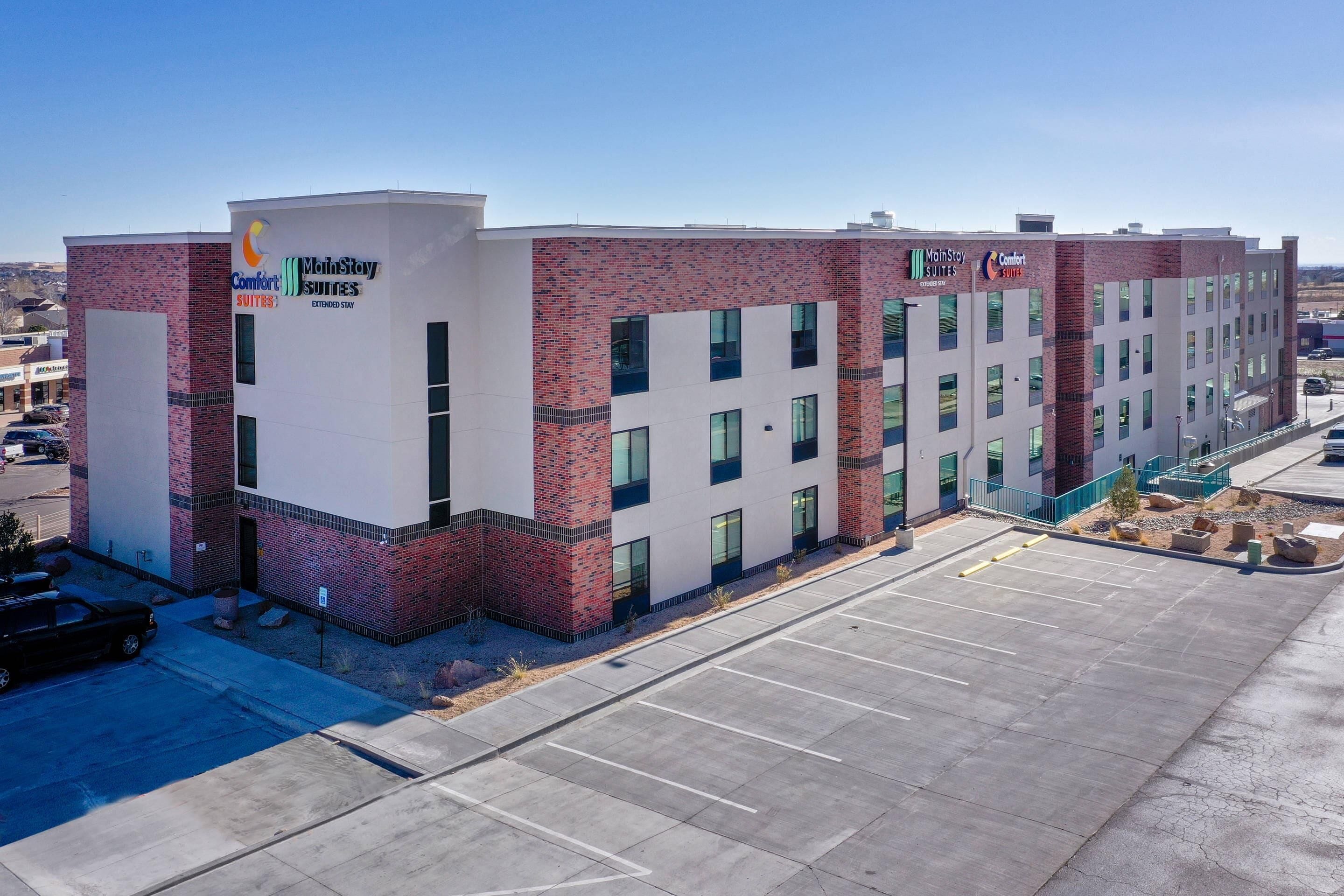 A modern hotel with a brick facade, multiple windows, and a parking lot.