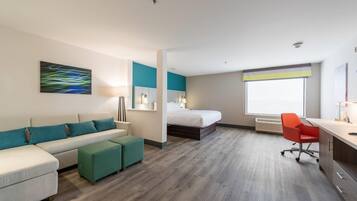 Quarto de hotel moderno com sofá, cama, escrivaninha e janela.