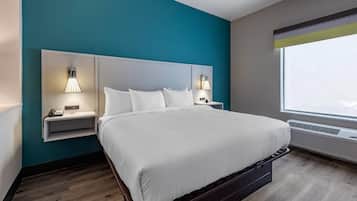 Una habitación de hotel moderna con una pared de acento color verde azulado, una cama grande con ropa de cama blanca, dos mesitas de noche con lámparas y una ventana con vistas.