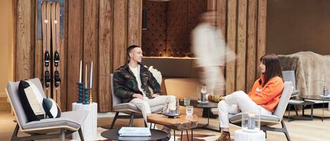 A modern interior with wooden paneling, a ski rack, and a cozy seating area with a cowhide rug.