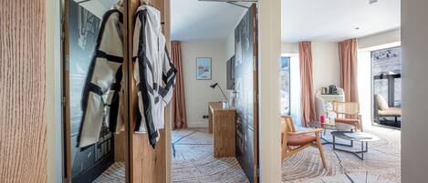 Une chambre d’hôtel dotée d’un grand miroir, d’une armoire en bois, d’un coin salon avec une table et des chaises, et offrant une vue sur l’extérieur.