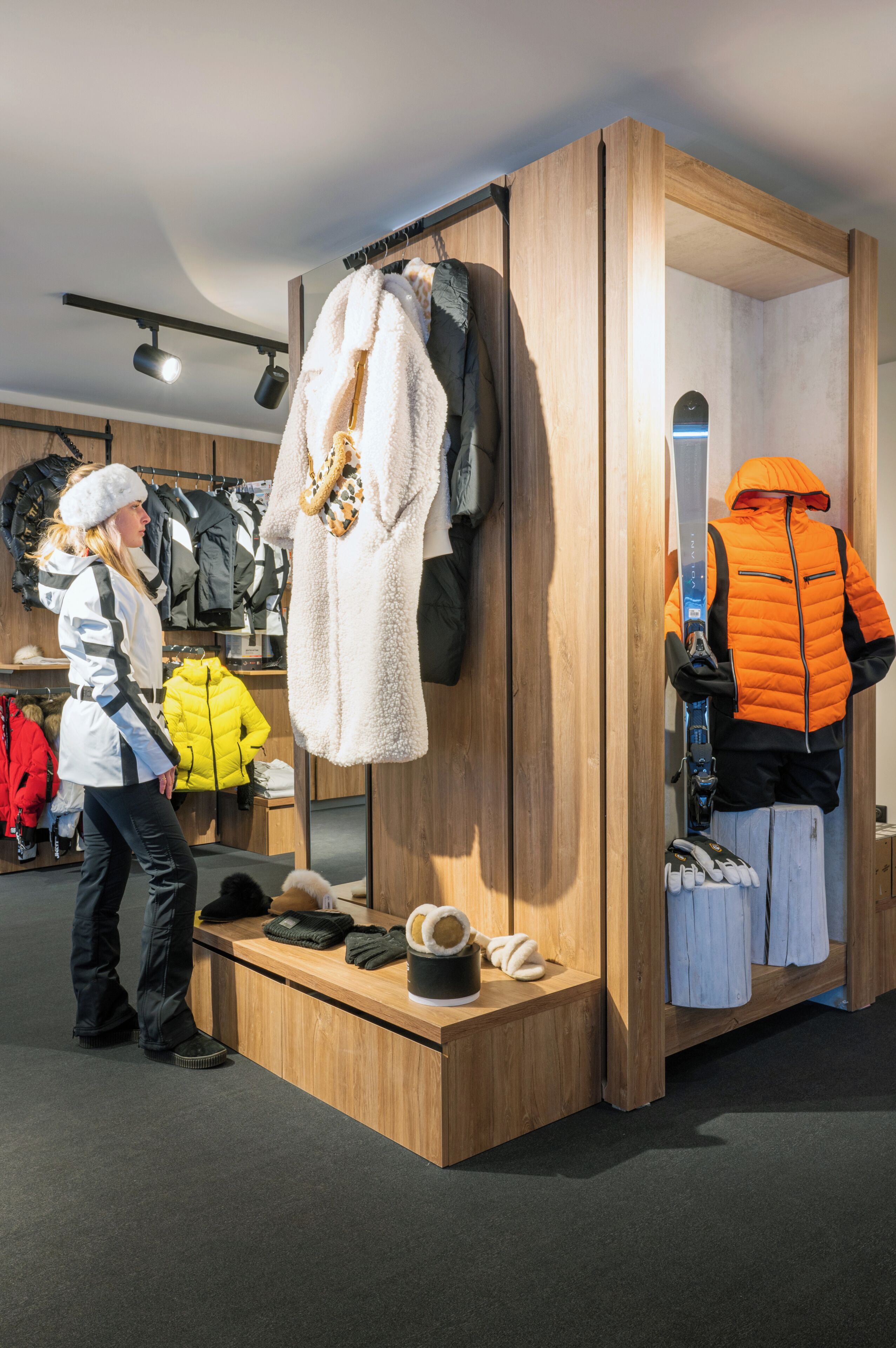 A clothing store with wooden display units, a mannequin, and various winter jackets.