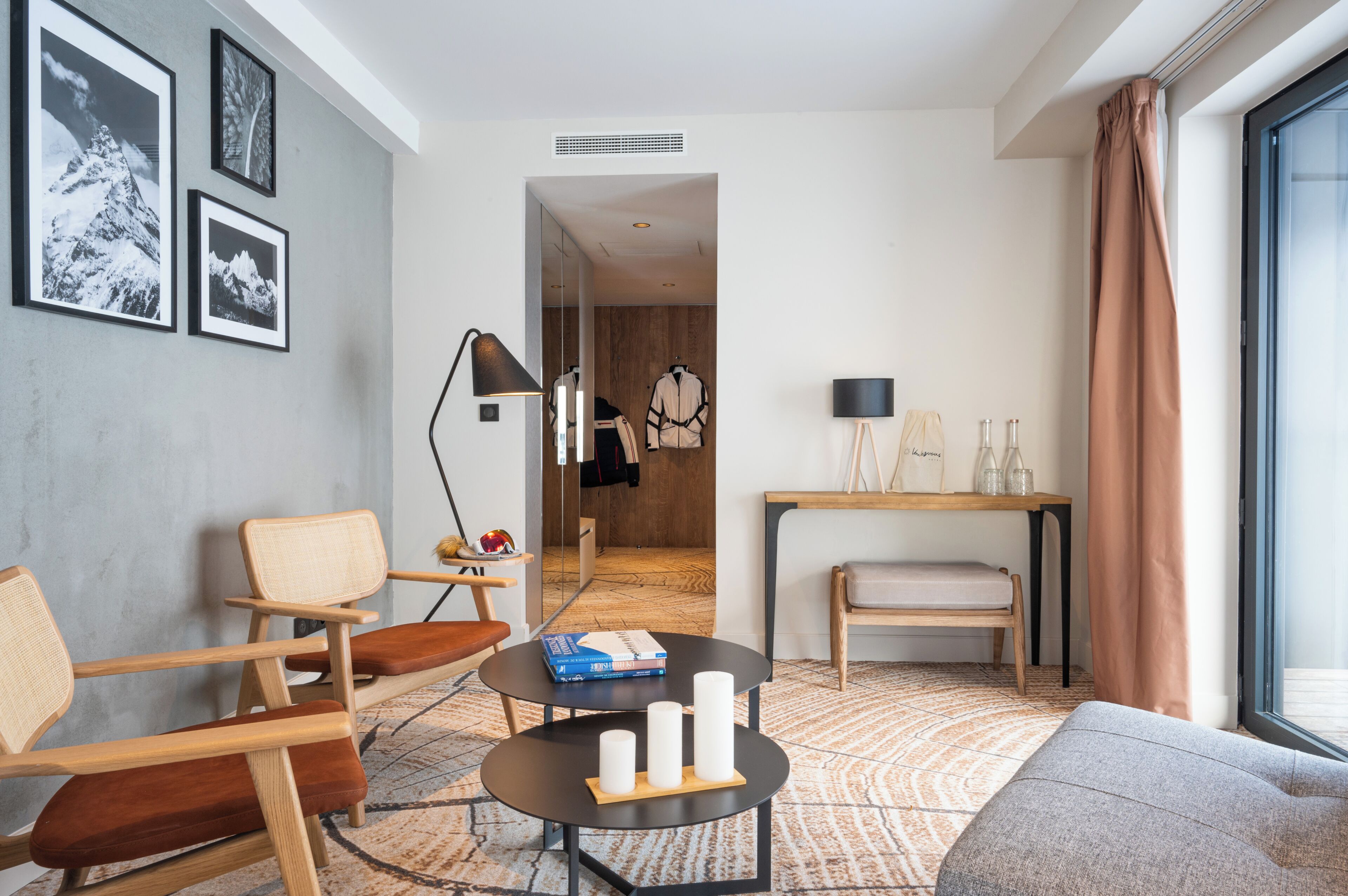A modern living room with a sofa, chairs, a coffee table, and a view of a hallway.