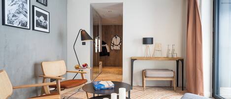 A modern living room with a sofa, chairs, a coffee table, and a view of a hallway.