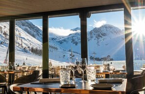 A restaurant with a mountain view, tables set with wine glasses, and a ski lift in the background. - Hôtel VoulezVous by Les Etincelles  (Tignes)