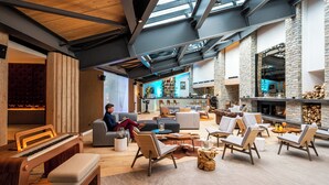 Un salón amplio con un piano, zonas de estar, una chimenea y un techo alto con tragaluces.