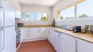 Una cocina moderna con armarios blancos, microondas, tostadora y lavavajillas.