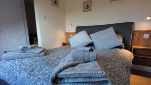 Un letto rifatto con cura, una comodino con una lampada e un quadro incorniciato appeso al muro.