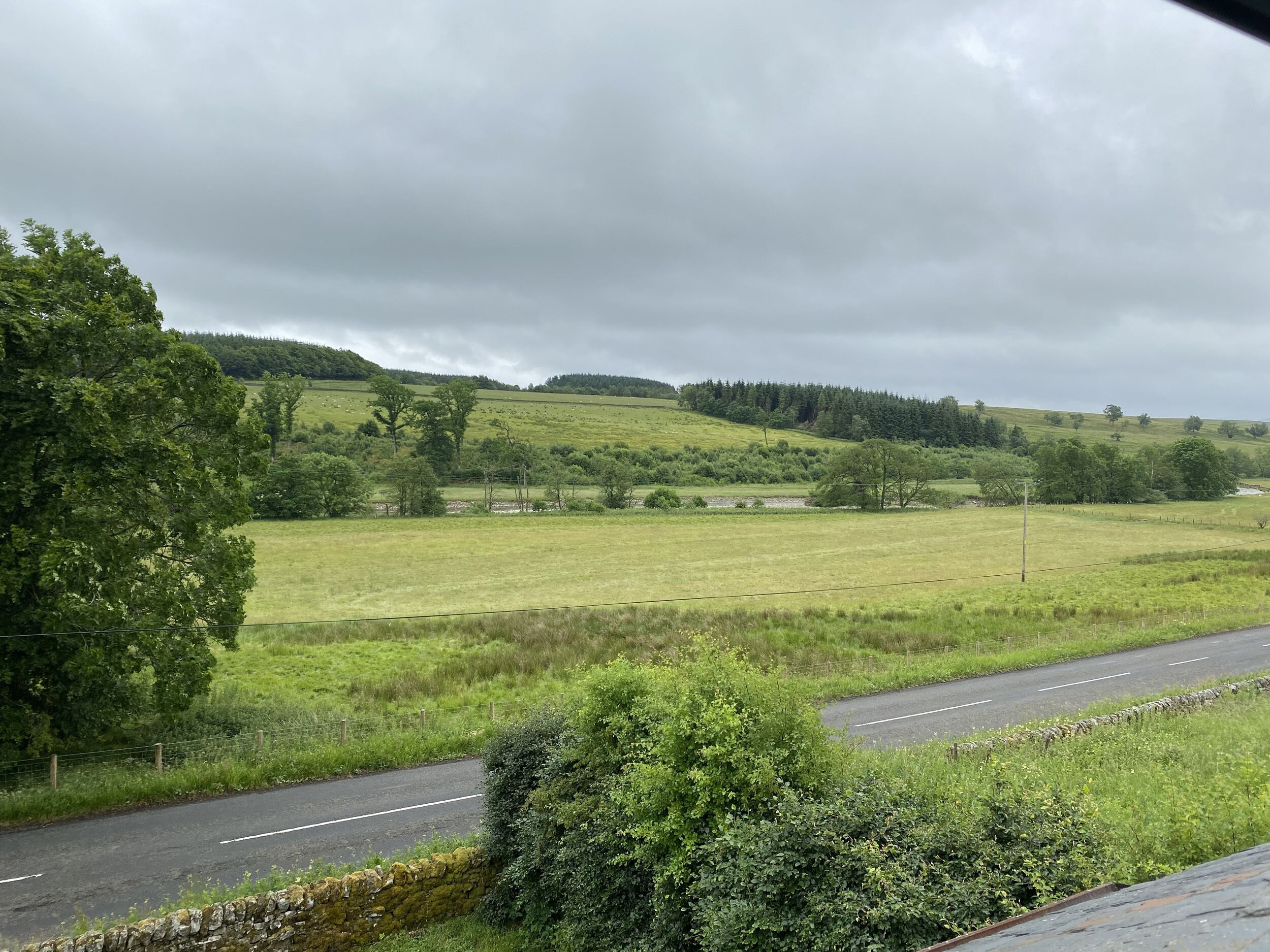 A rural landscape with a road curving through fields and hills.