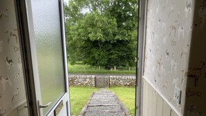 A doorway leading to a stone pathway outside. - Netherraw (Hawick)