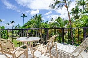 A balcony with a round table and two chairs, surrounded by a metal railing.