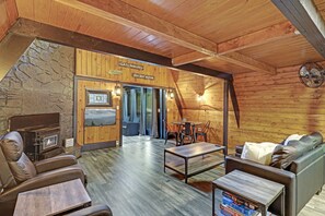 L’intérieur chaleureux d’un chalet en bois, avec une cheminée en pierre, des fauteuils en cuir et une vue sur les montagnes.
