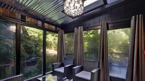 Une chambre moderne dotée de grandes fenêtres, de meubles en osier et d’un lustre.