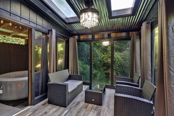 Un intérieur moderne avec un patio vitré, des meubles en osier et un lustre.